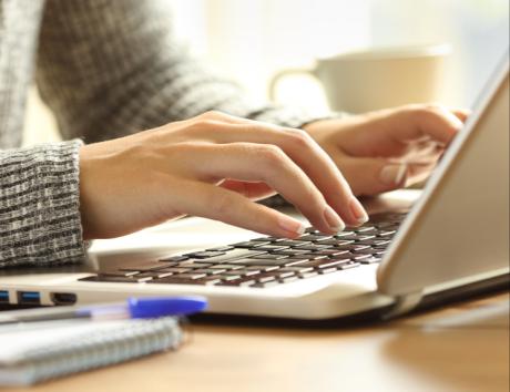 Mains tapant sur un ordinateur, illustrant la création d’un CV avec Microsoft Word