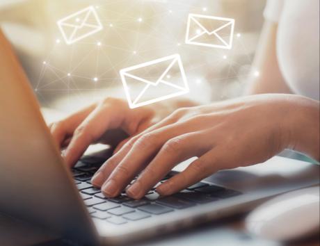 Mani che scrivono su computer con grafiche sovraimpresse di buste da lettera per indicare guida completa per aggiungere l'email sul proprio curriculum