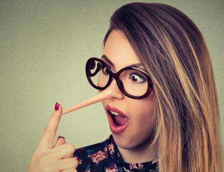 Femme touchant un long nez exagéré pour illustrer le fait de mentir sur un CV