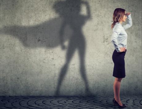 Immagine di professionista a figura intera di profilo con ombra di WonderWoman sullo sfondo per indicare obiettivi professionali su Curriculum Vitae