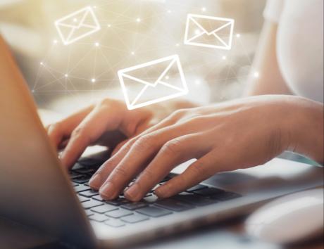 Imagen de una persona tecleando e ilustraciones de correo superpuestas para ejemplificar cómo enviar un currículum por correo